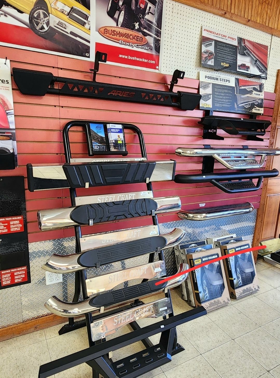 Display of black tow hooks and accessories on a slatwall in a shop, with posters above.