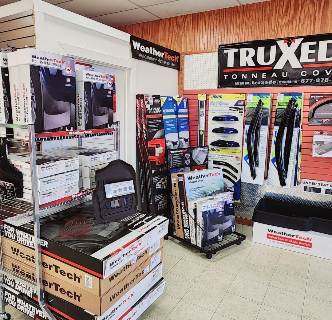 Automotive accessories display with TRUXEDO banners, floor mats, and truck bed covers in a showroom
