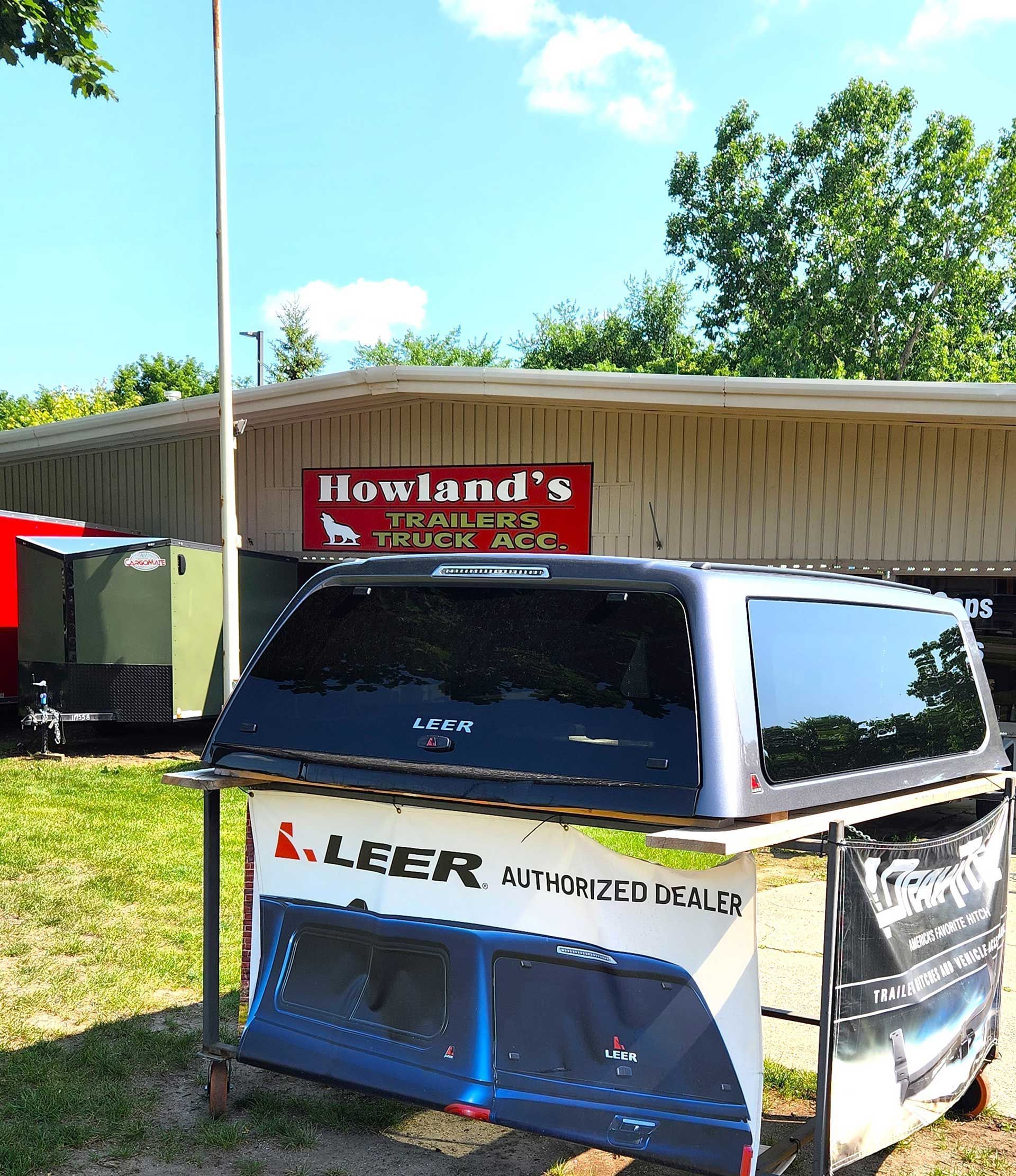 Small blue-and-white off-road vehicle parked outside a building with a red sign under a sunny sky