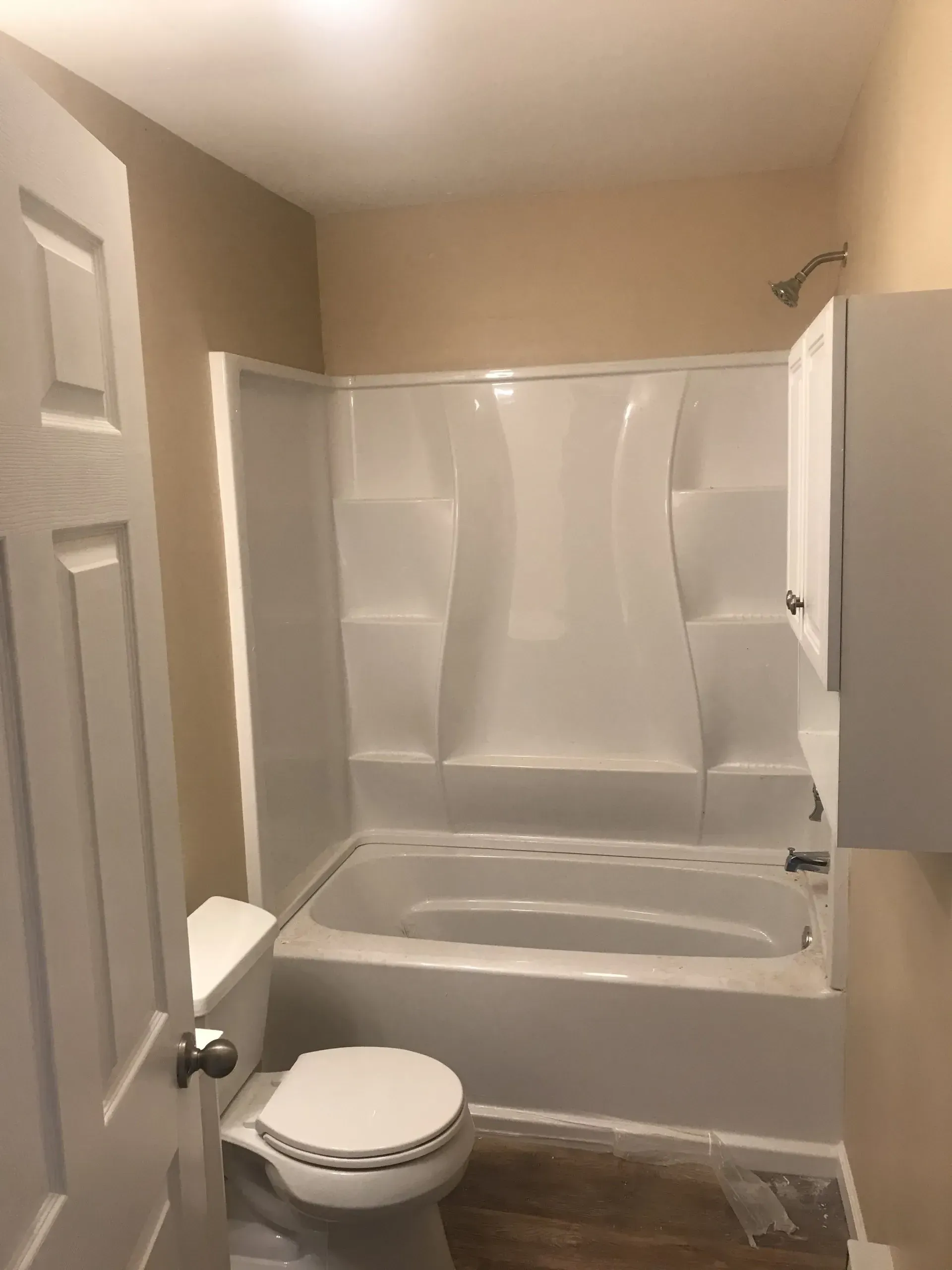 Bathroom with toilet and bathtub fitted with a white accessible transfer bench and shower surround