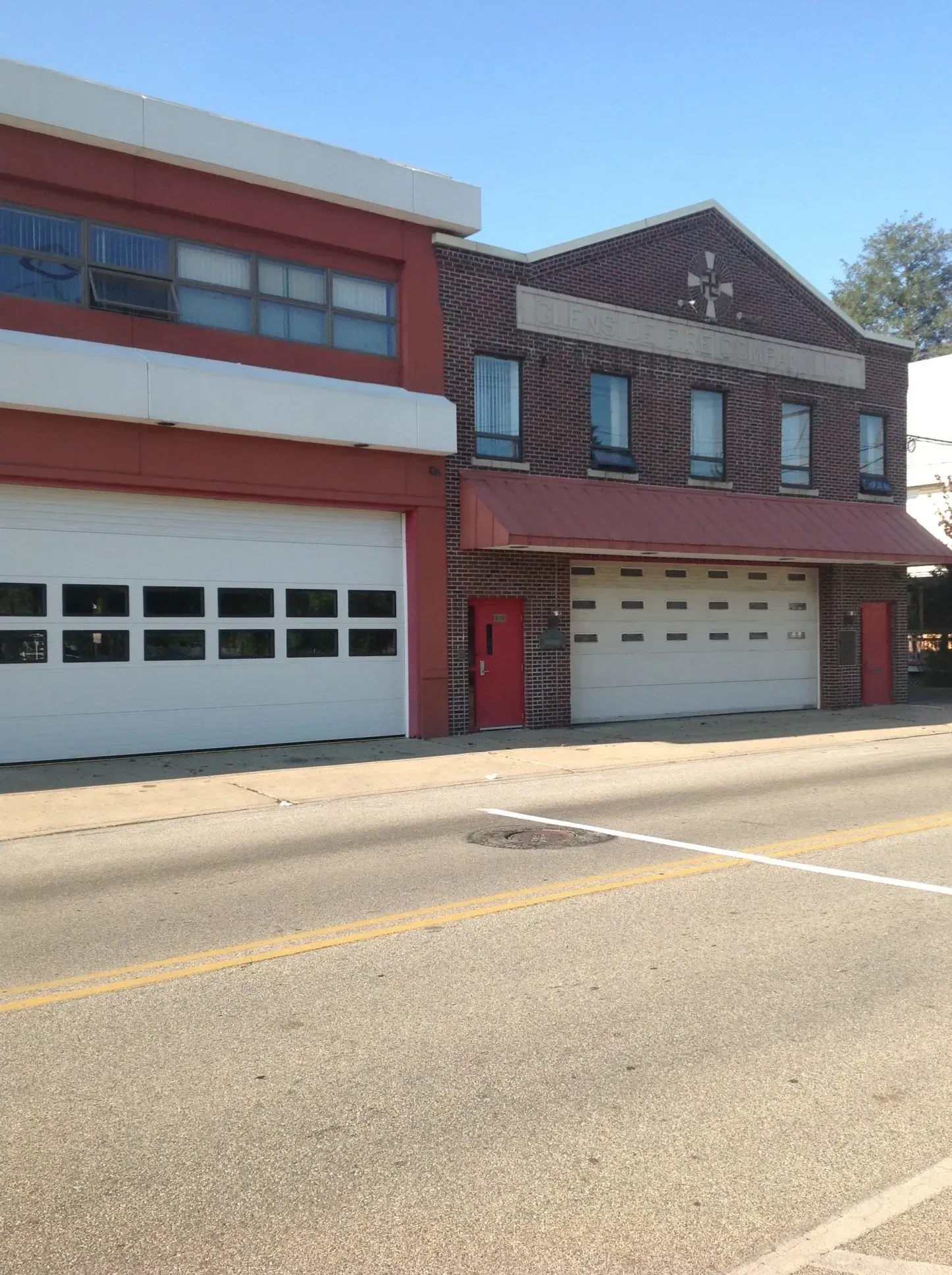 Two adjoining fire stations with large garage doors on a sunny street