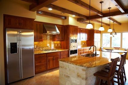 A kitchen with wood cabinets, granite countertops, stainless steel appliances, and a stone island.