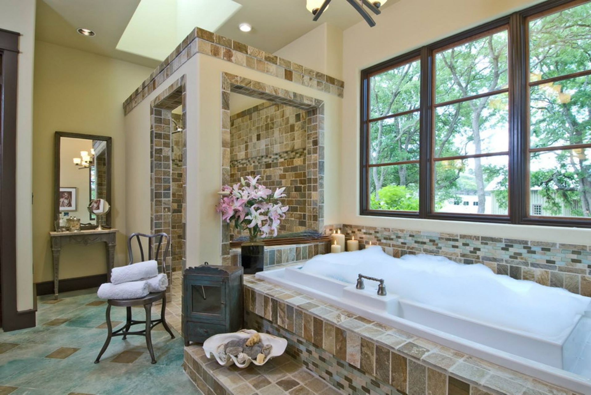 Luxurious bathroom with a large tub filled with bubbles, surrounded by stone tiles.