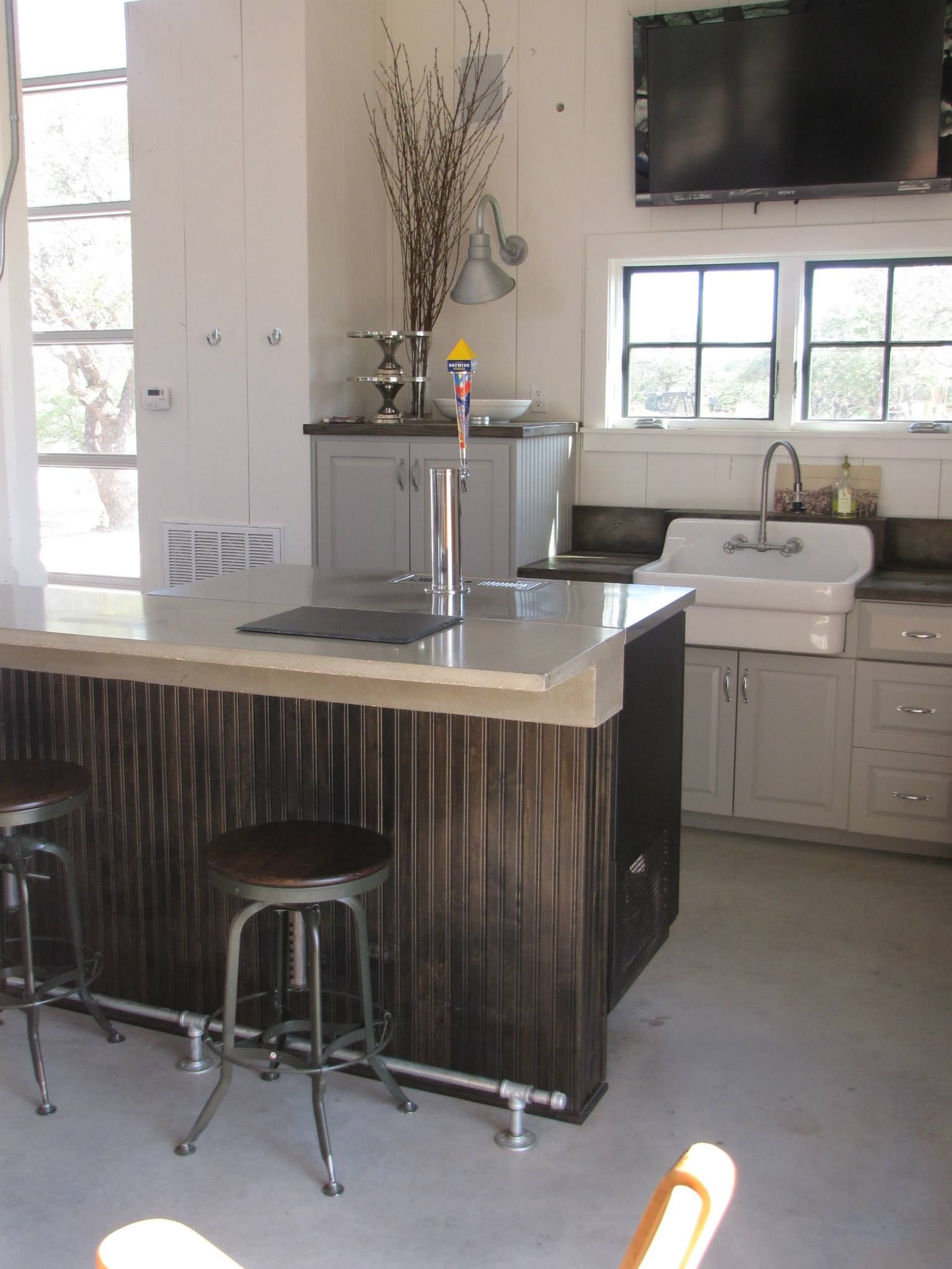 Kitchen with a bar, stools, sink, cabinets, and a tap. Gray and brown color scheme.