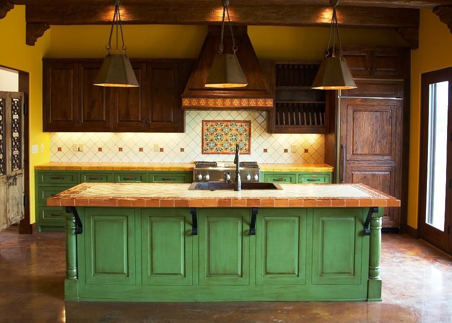 Green island kitchen with brown cabinets, yellow walls, and hanging lights.