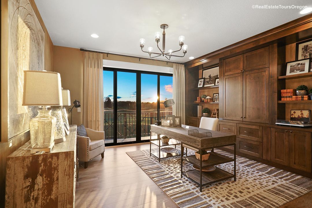 A living room with a desk , chairs , lamps and a balcony.