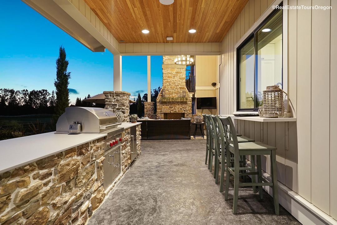 A large outdoor kitchen with a grill and a fireplace