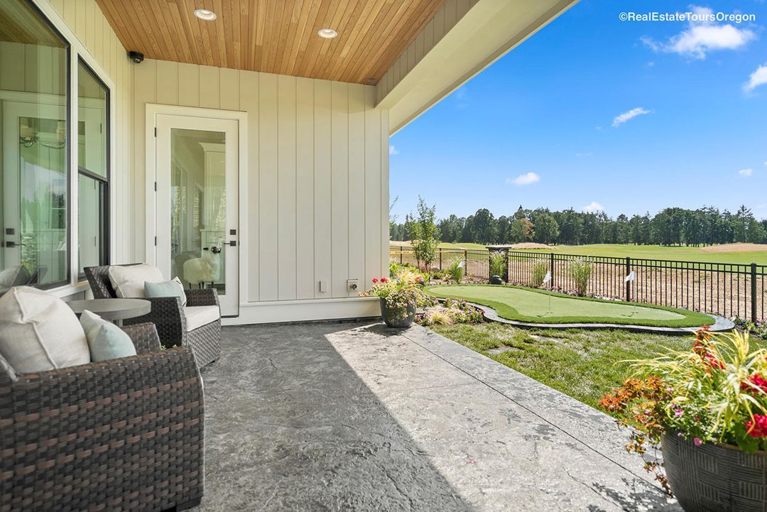 A porch with a couch and chairs and a view of a golf course.