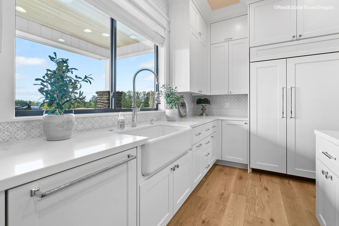 A kitchen with white cabinets , a sink , and a window.