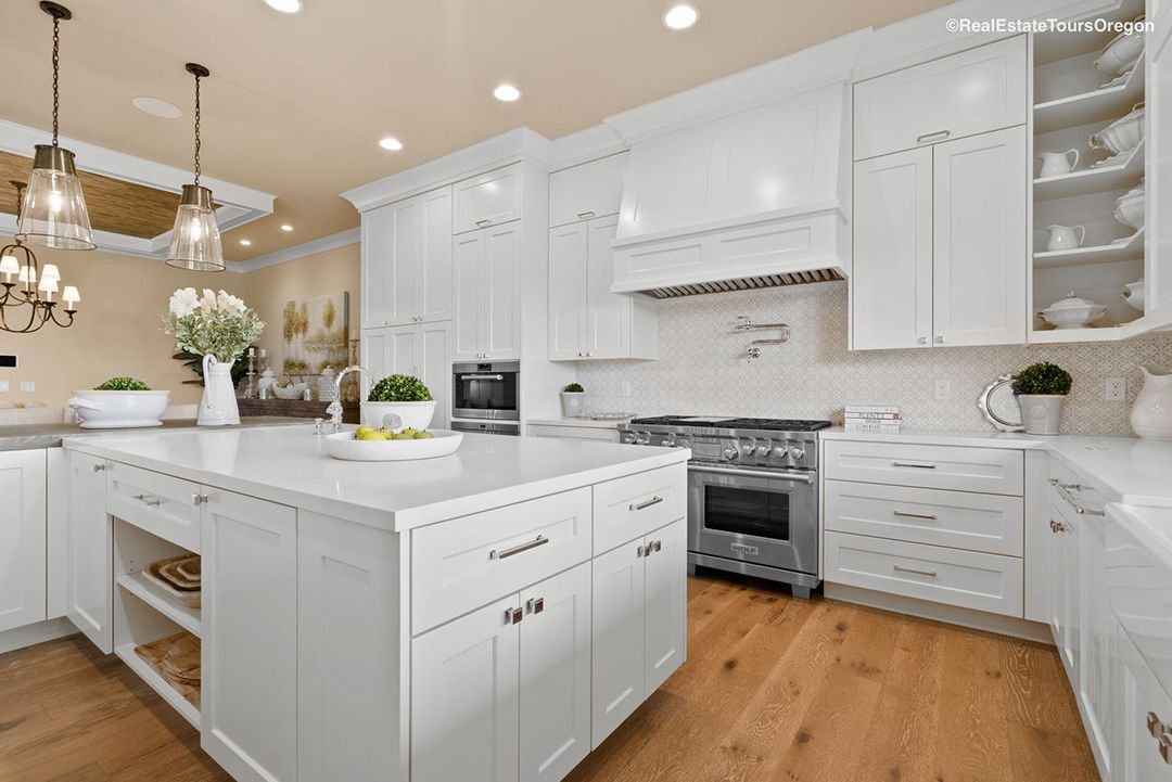 A kitchen with white cabinets , stainless steel appliances , and a large island.