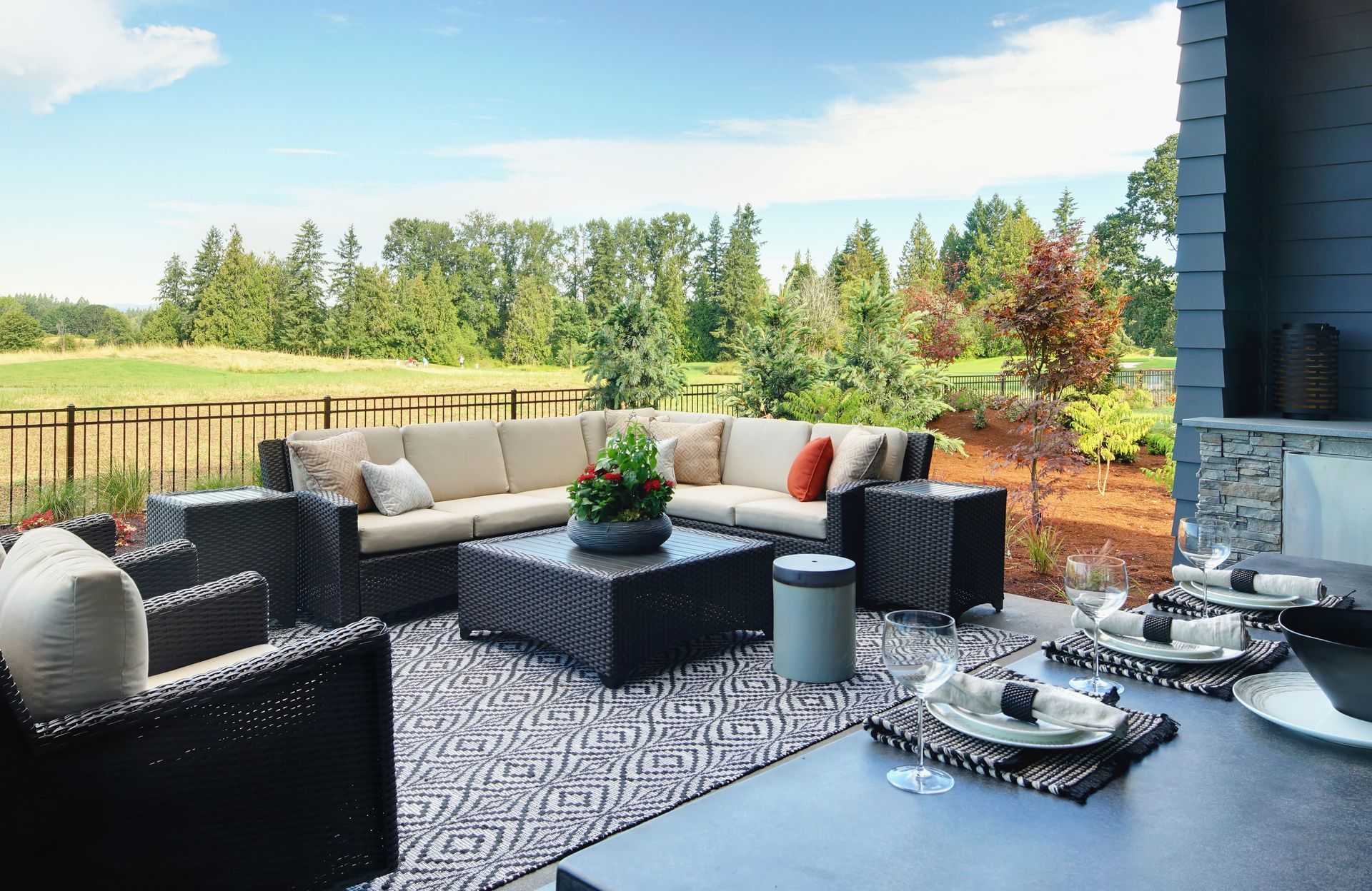 A patio with a couch , chairs , a table and a fireplace.