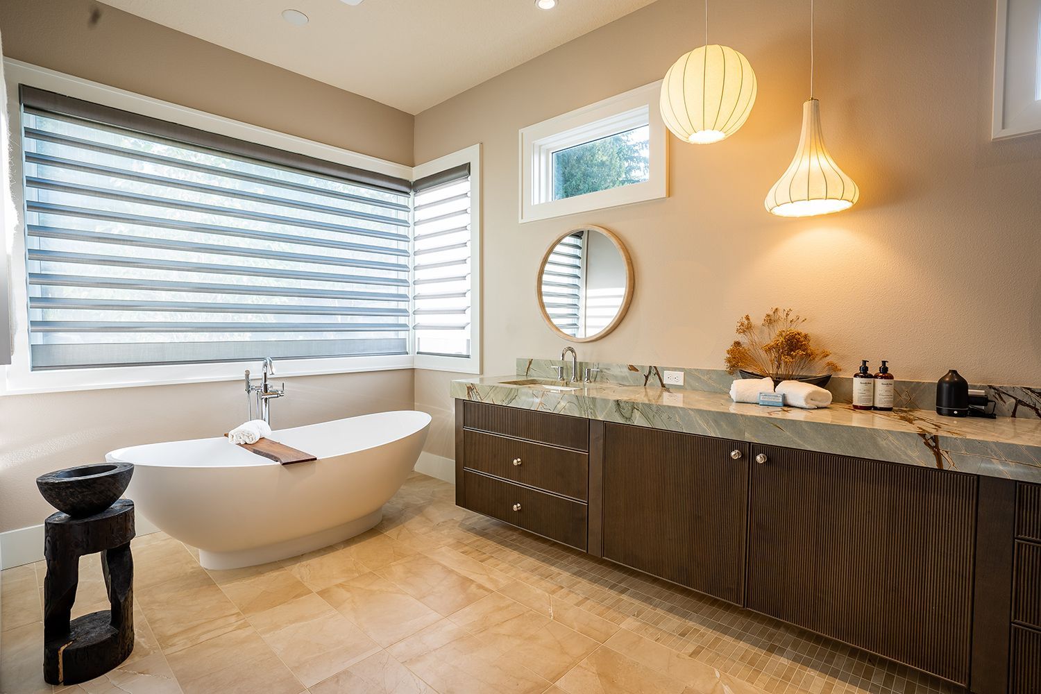 A bathroom with a tub , sink , mirror and window.