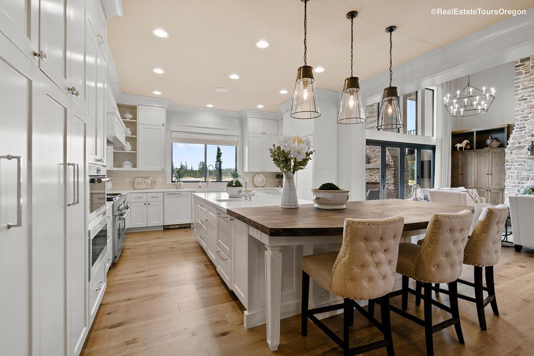 A kitchen with white cabinets , wooden floors , and a large island.