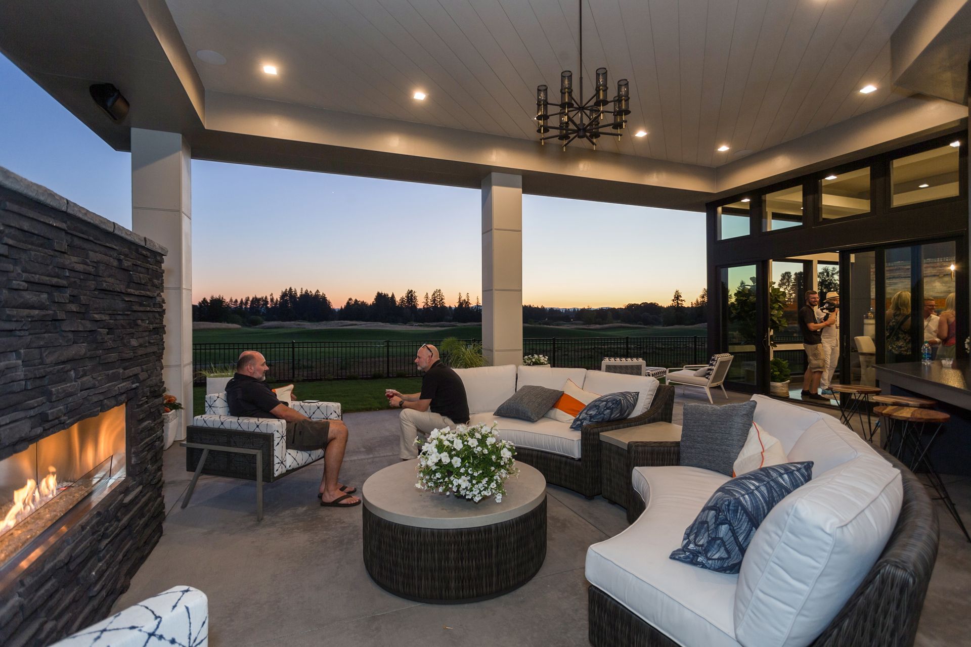 Two men are sitting on a patio in front of a fireplace
