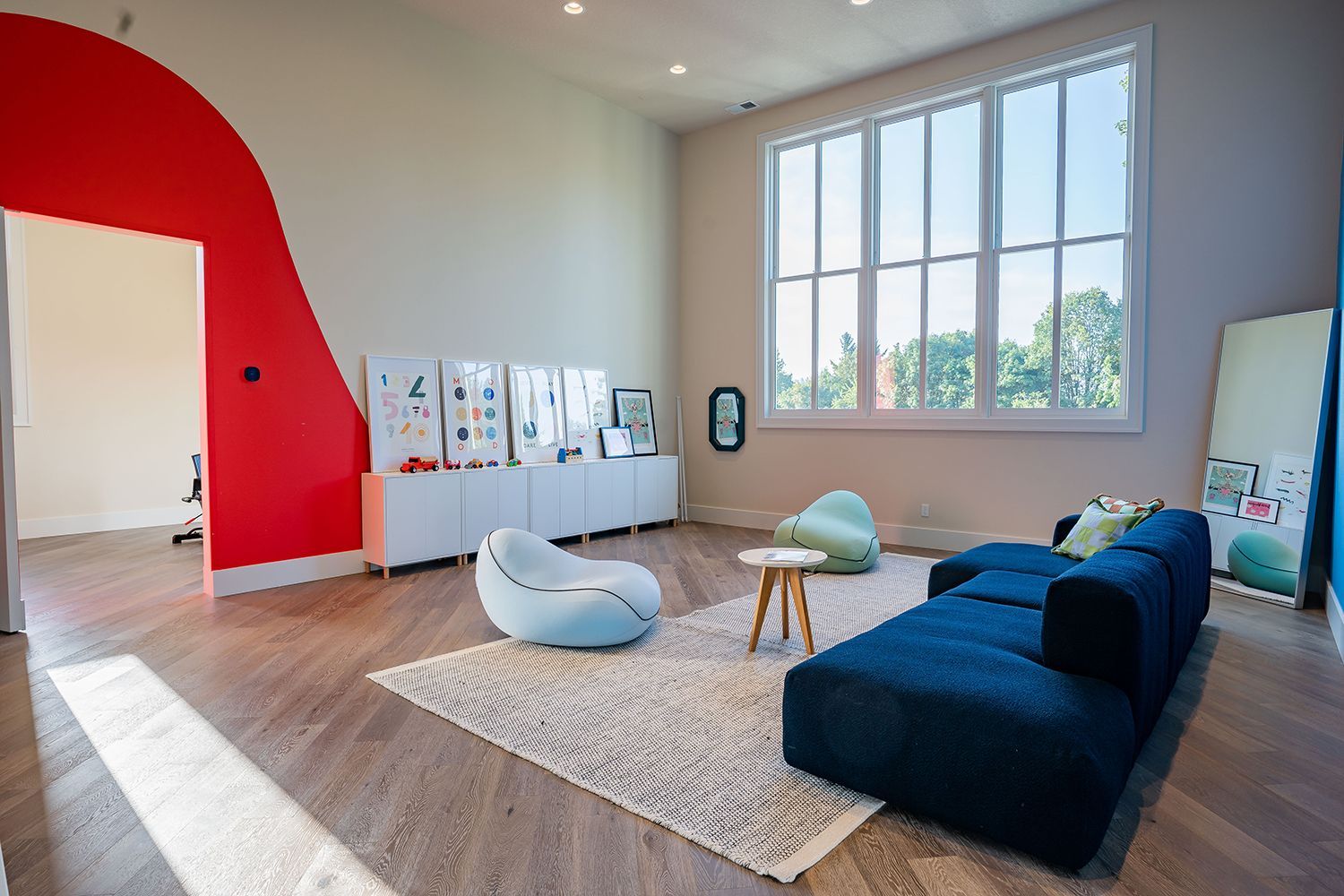 A living room with a blue couch , chairs , and a large window.