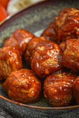 Meatballs in a brown sauce, served in a speckled gray bowl.