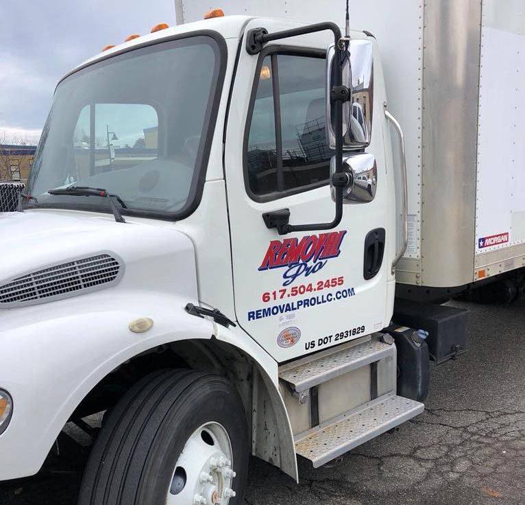 A white Removal Pro box truck parked on a paved lot, featuring the company logo and contact information on the door.