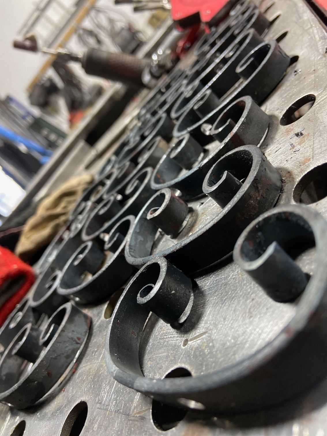 Black metal scrollwork arranged on a metal surface, possibly for a decorative fence.