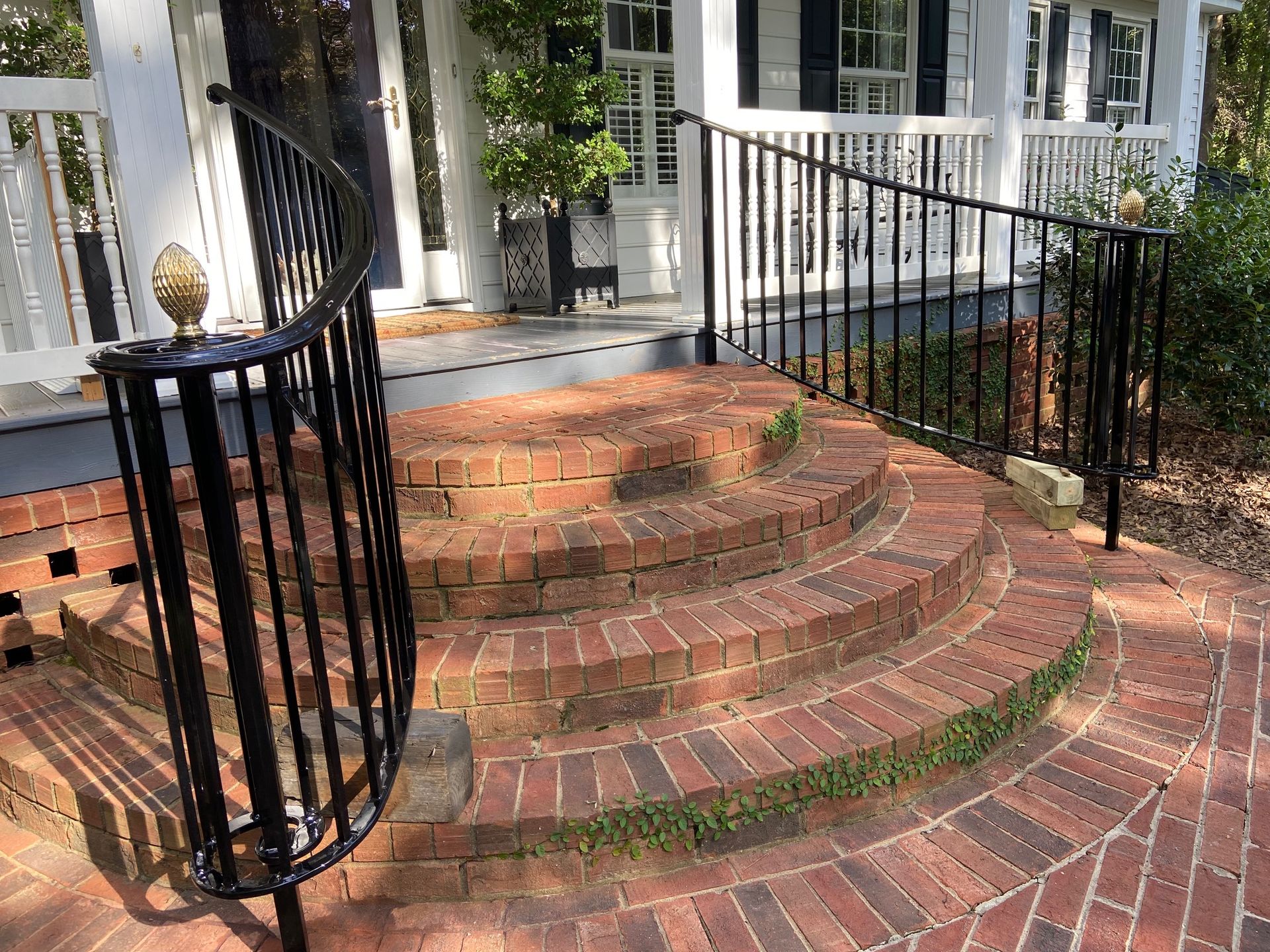 Brick steps with black railing leading to a porch.