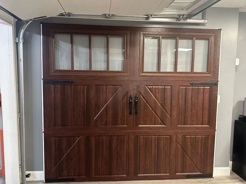 Dark brown garage door with windows, decorative handles and hinges.