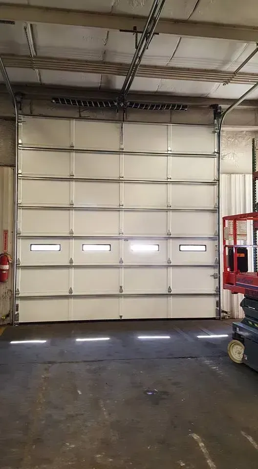 White industrial garage door with windows, closed in a warehouse.
