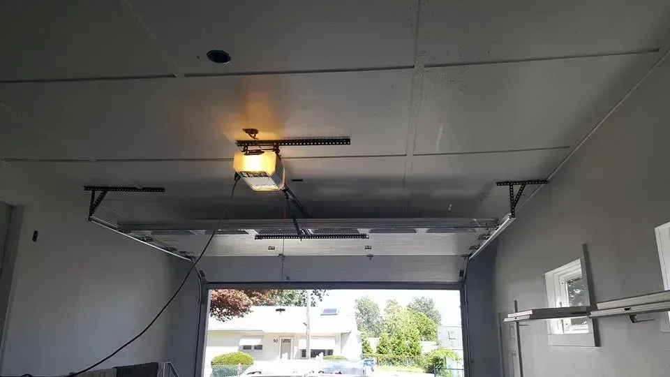 Open garage with a white ceiling, garage door opener, and exterior view.