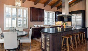 A kitchen with stainless steel appliances , a large island , a table and chairs.