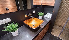 A bathroom with a sink , mirror , towels and potted plants.