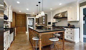 A kitchen with white cabinets , stainless steel appliances , and a large island.