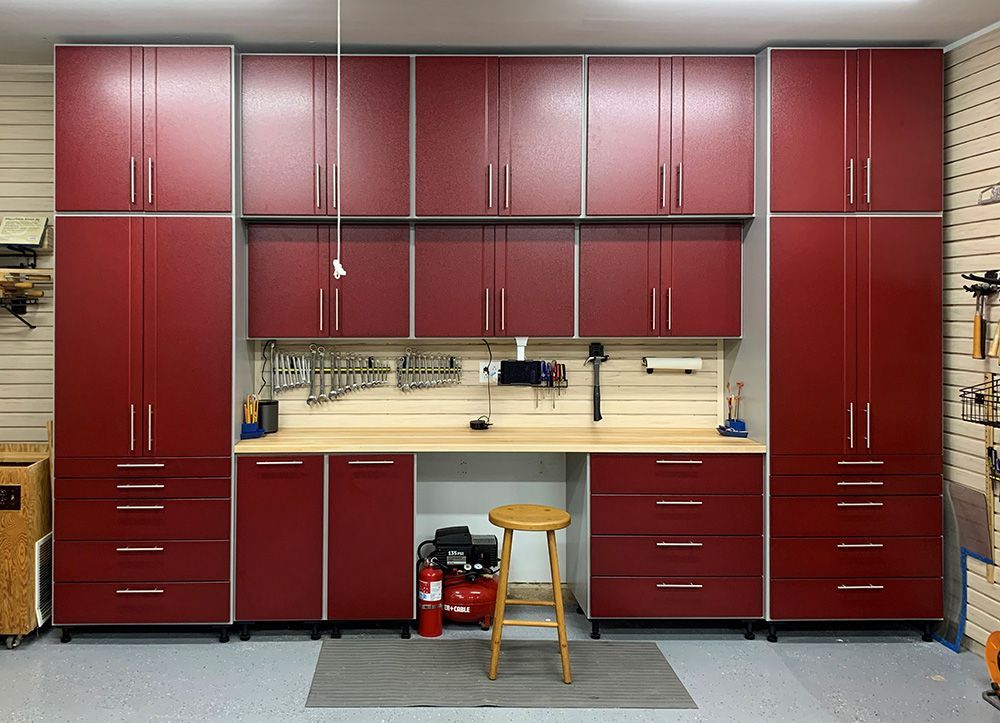 Red garage cabinets with silver trim, workbench, and tools. A stool sits in front of the workbench.