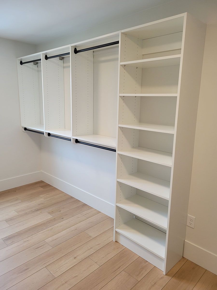 A walk-in closet with wooden floors and white shelves