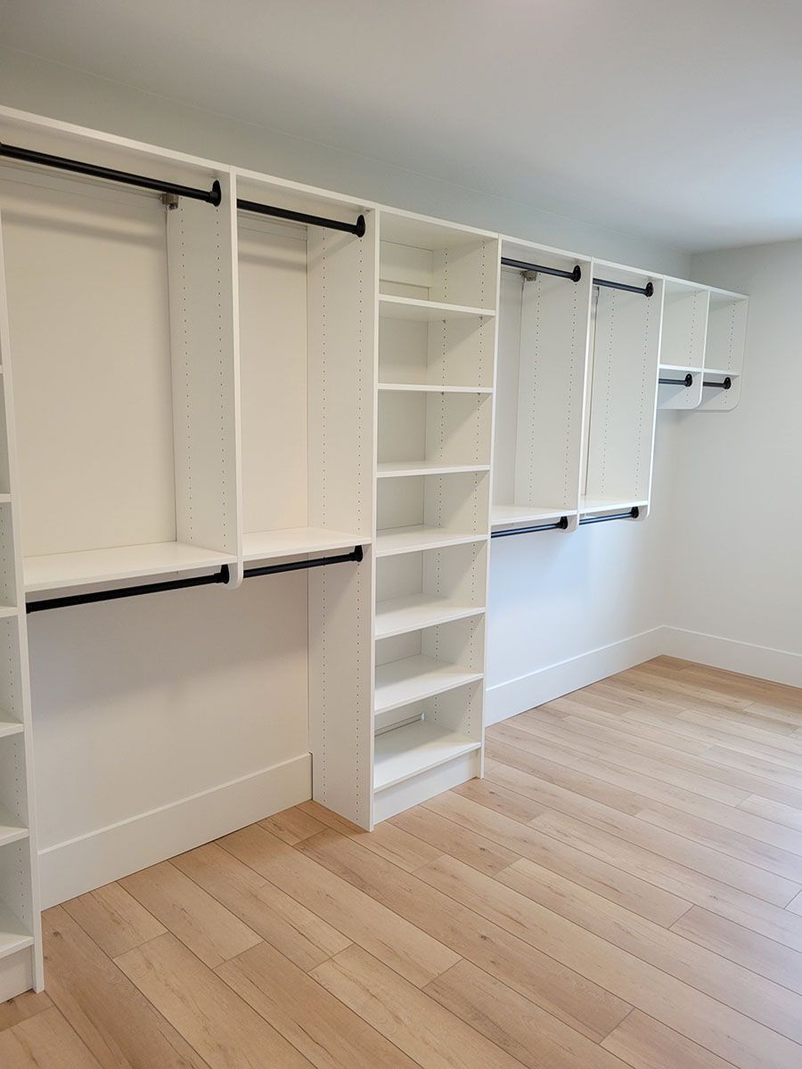 An empty walk-in closet with wooden floors and white shelves
