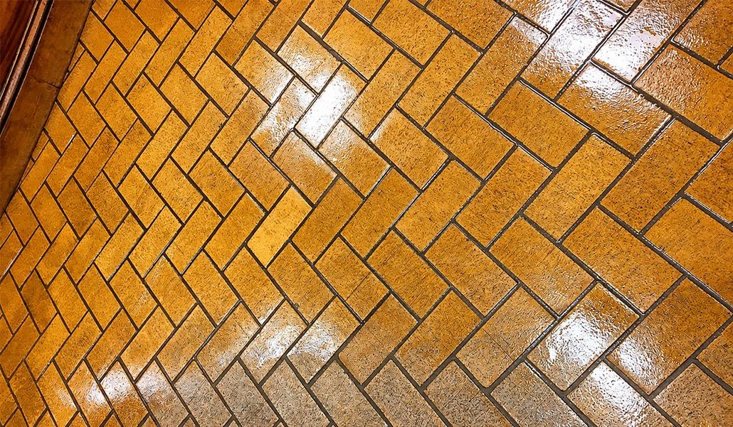 Wet orange brick pavement with diagonal herringbone pattern and reflections of light