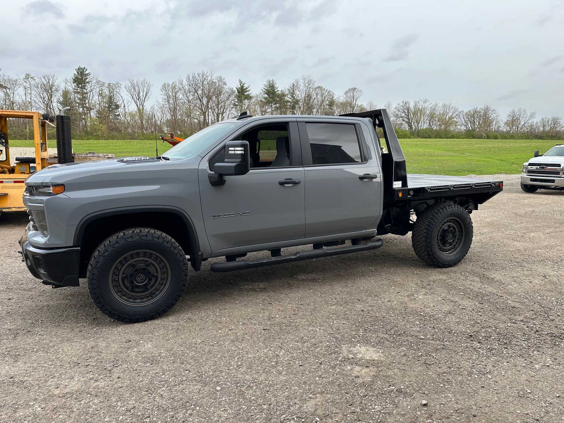 Gray Chevrolet truck with a flatbed, parked outdoors on gravel.