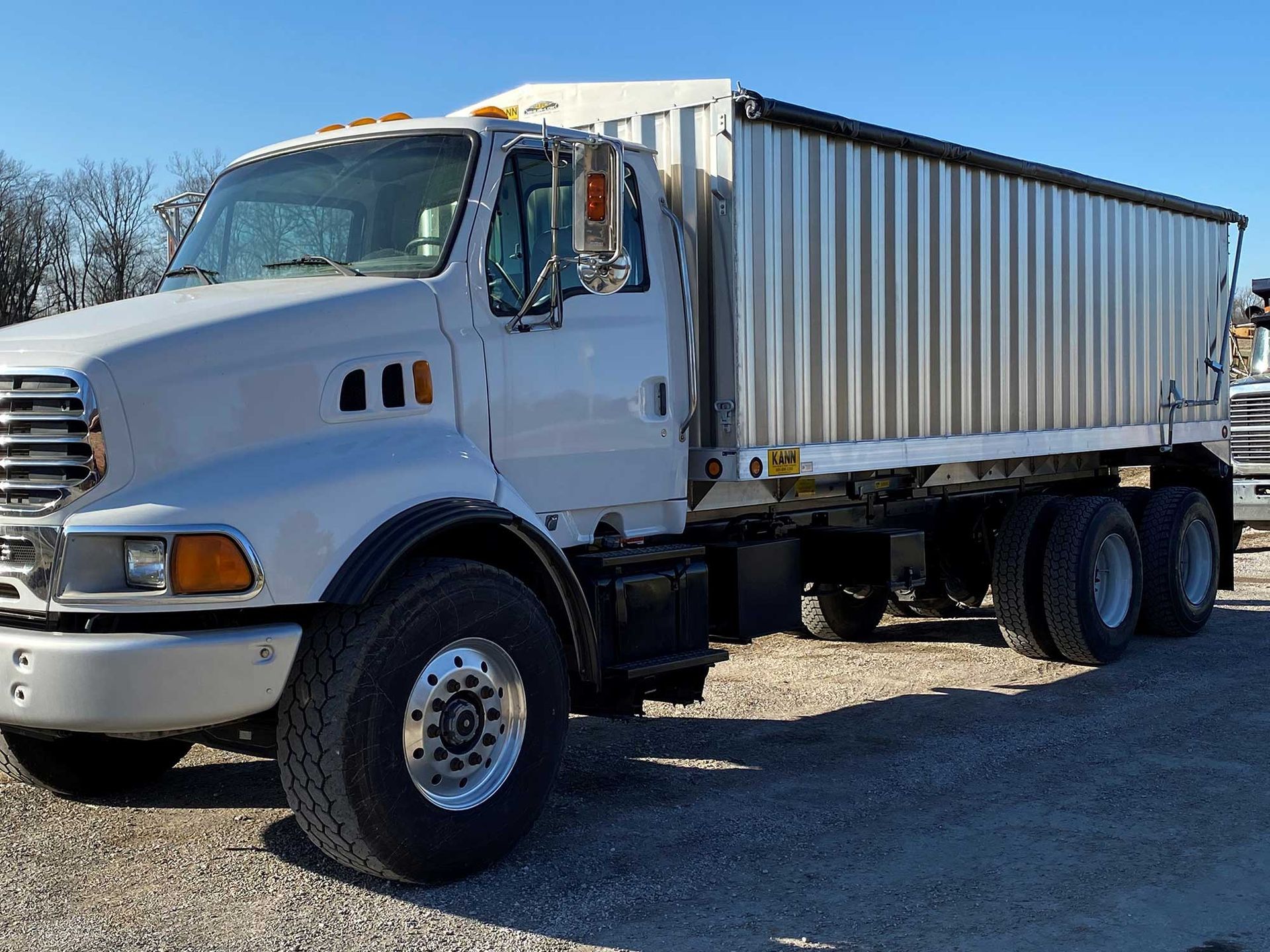White Sterling dump truck parked on a gravel lot.