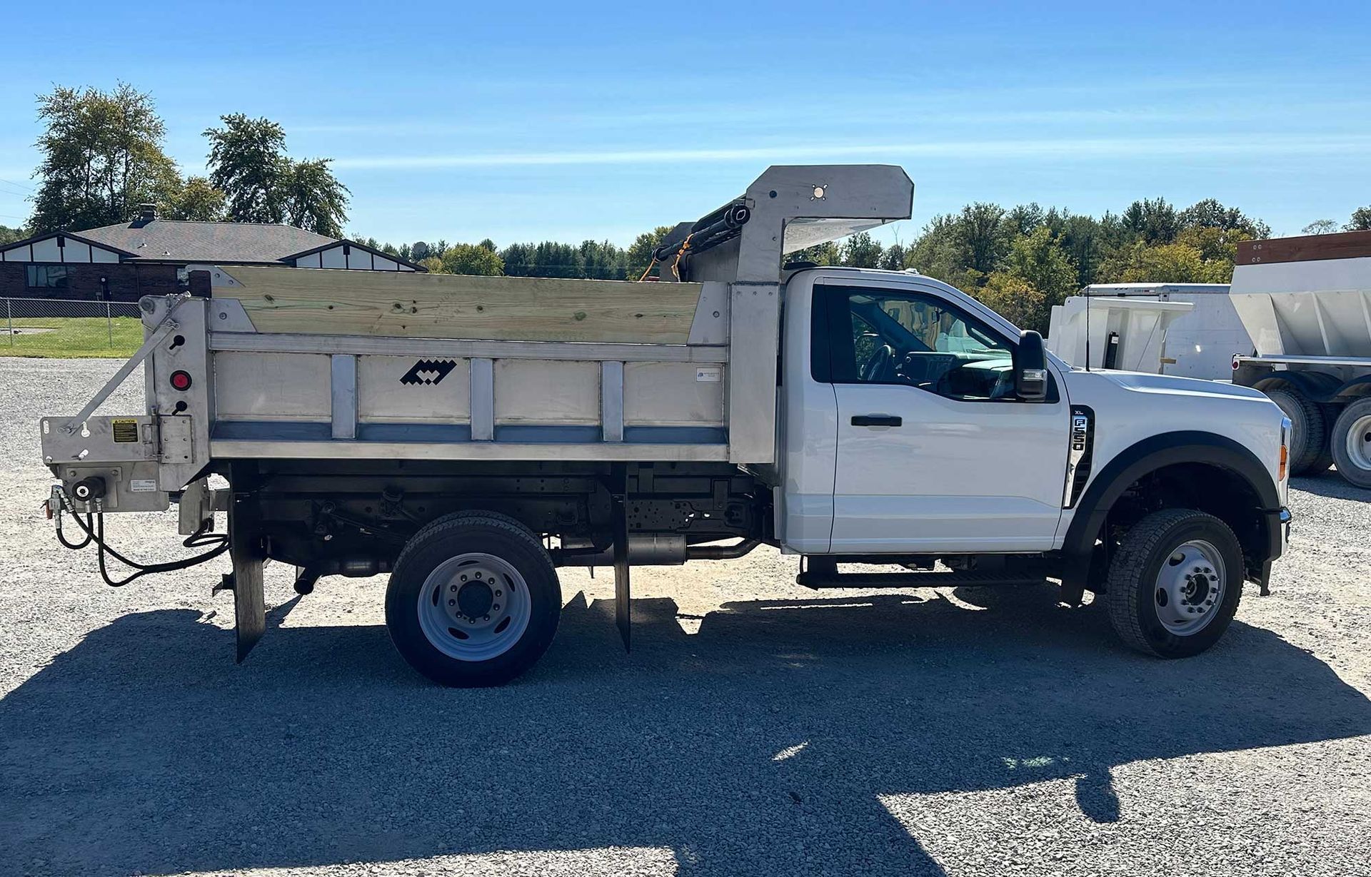 White Ford F-550 dump truck parked on gravel, under a clear blue sky.