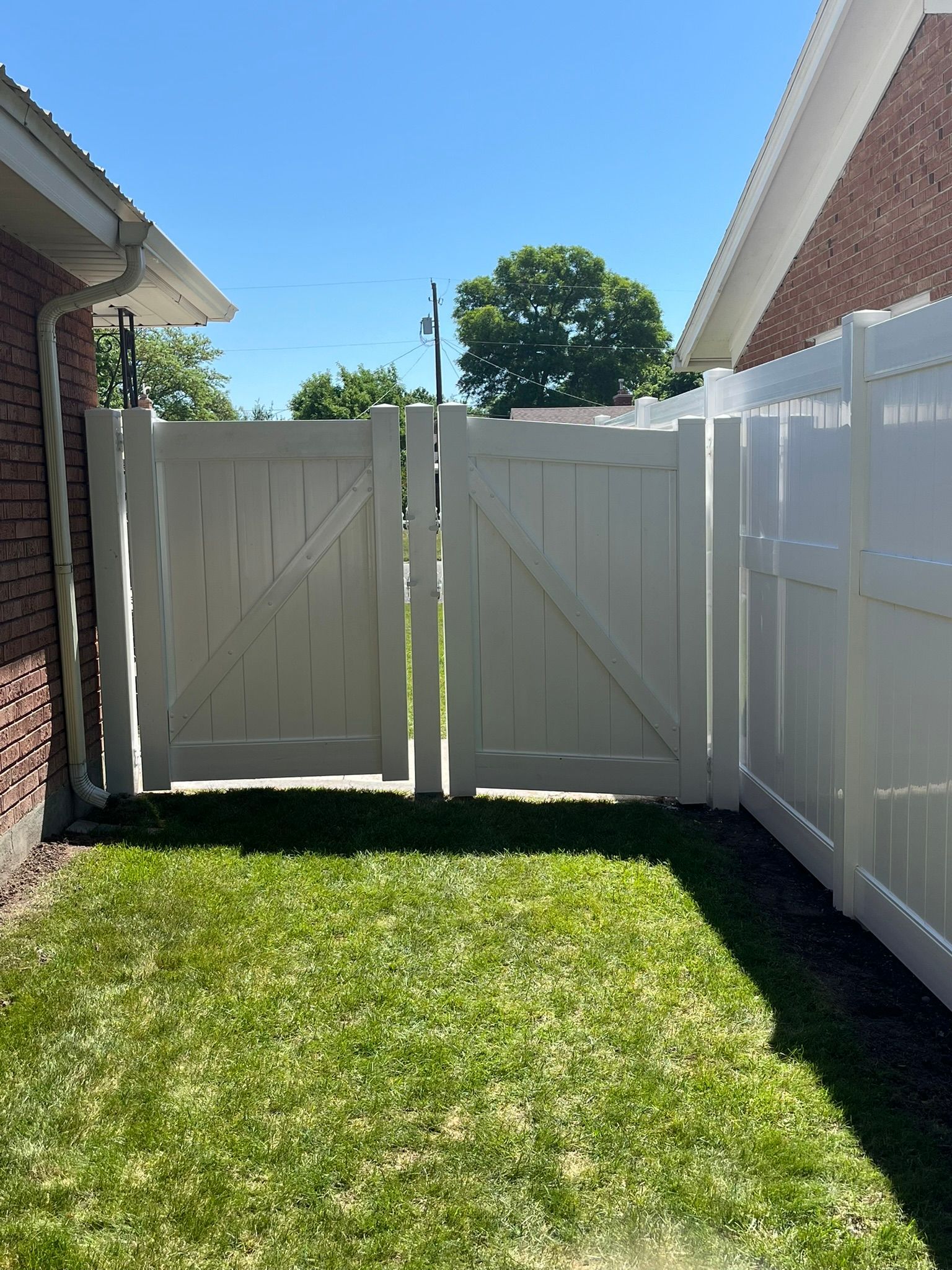 A white fence with a gate between two houses.