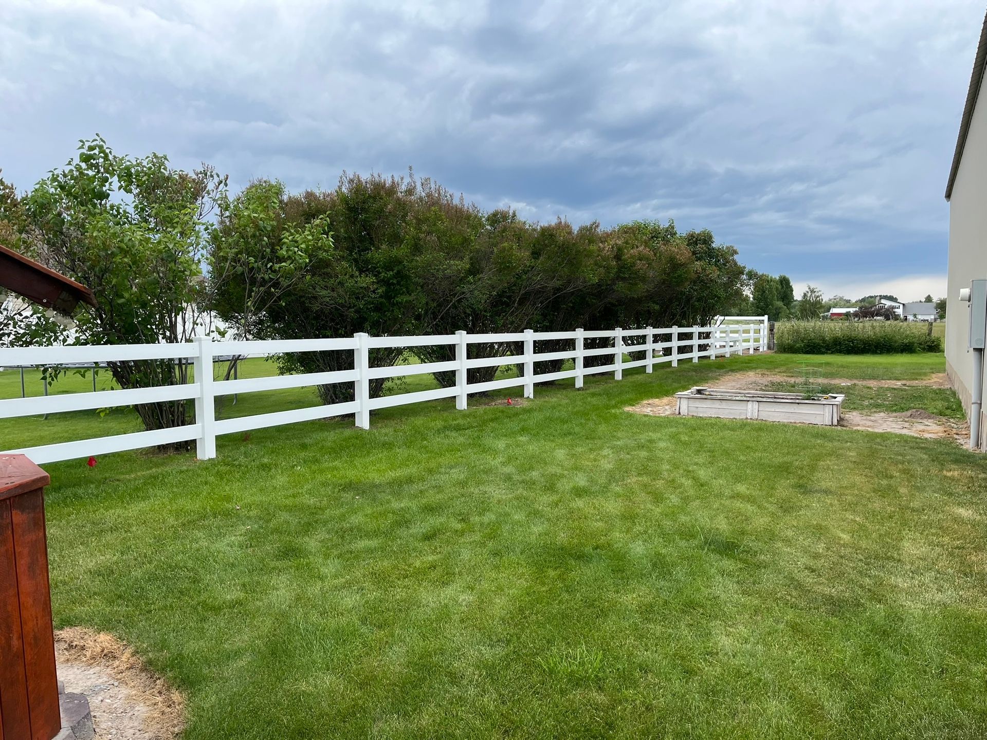 A white fence surrounds a lush green yard.