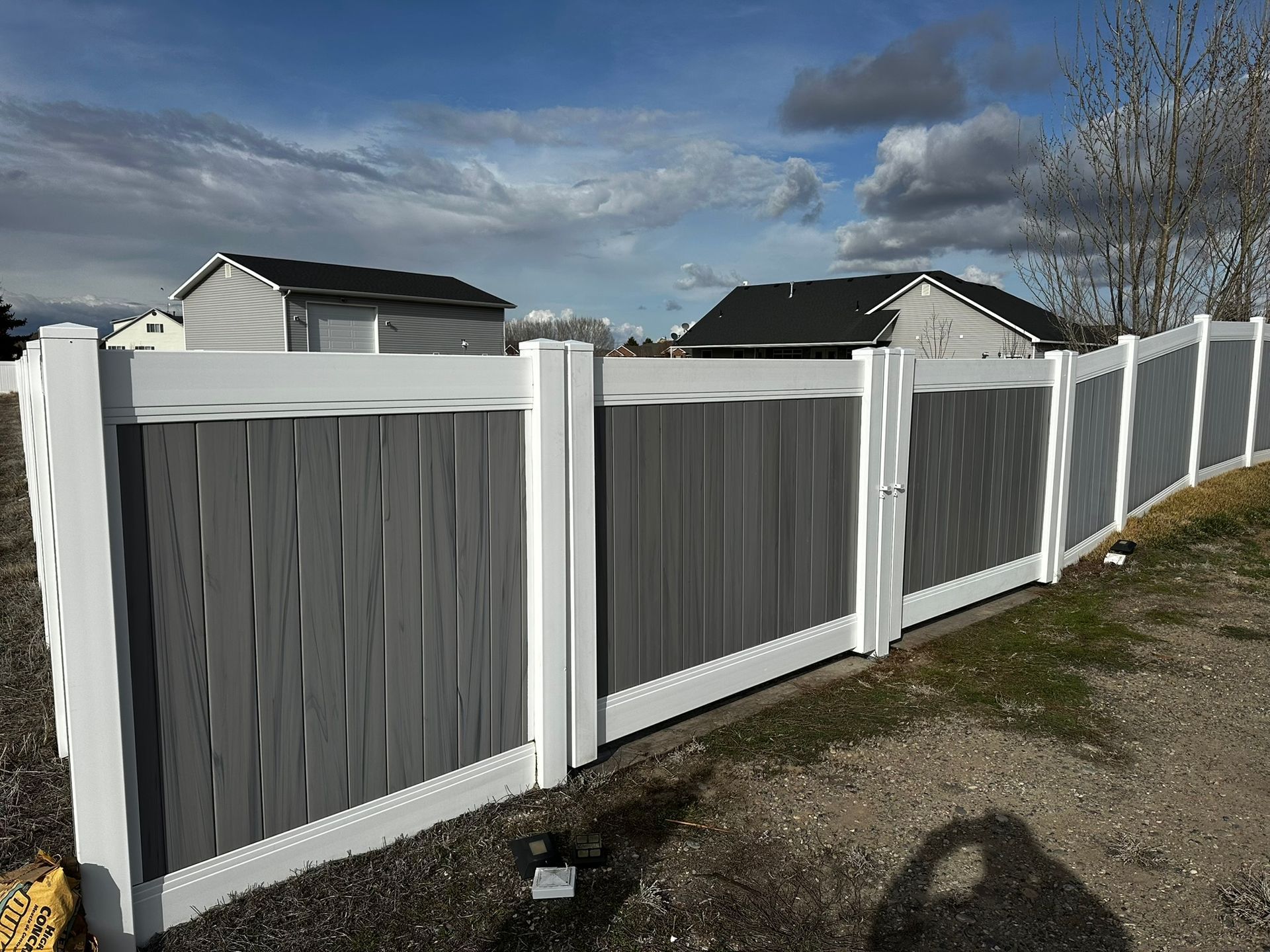 A gray and white fence with a gate in front of a house.