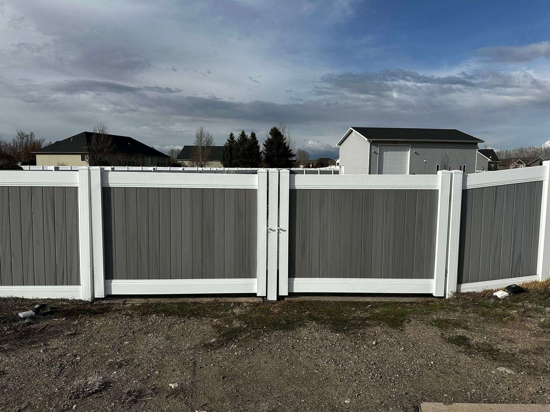 A gray and white fence with a gate in front of a house.