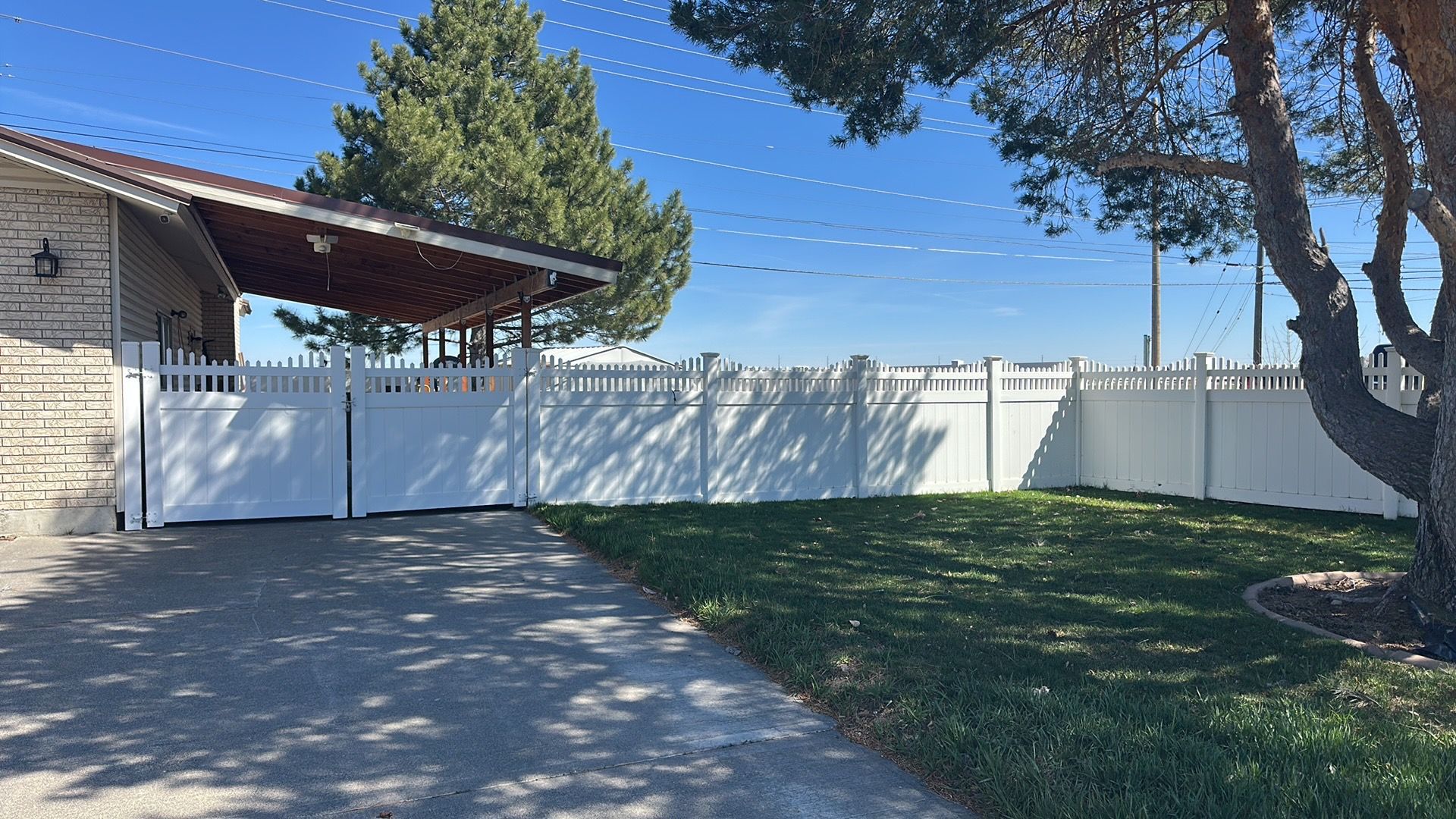 A white fence surrounds a house and a driveway.