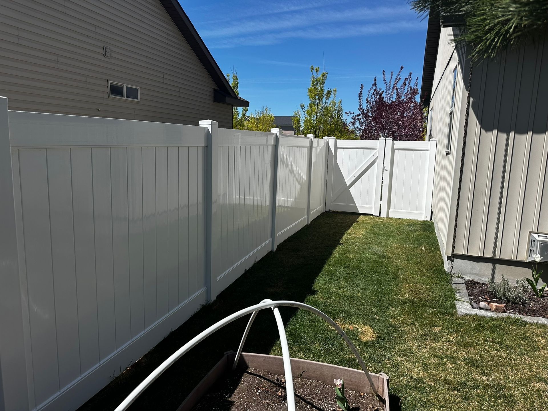 There is a white fence in the backyard of a house.