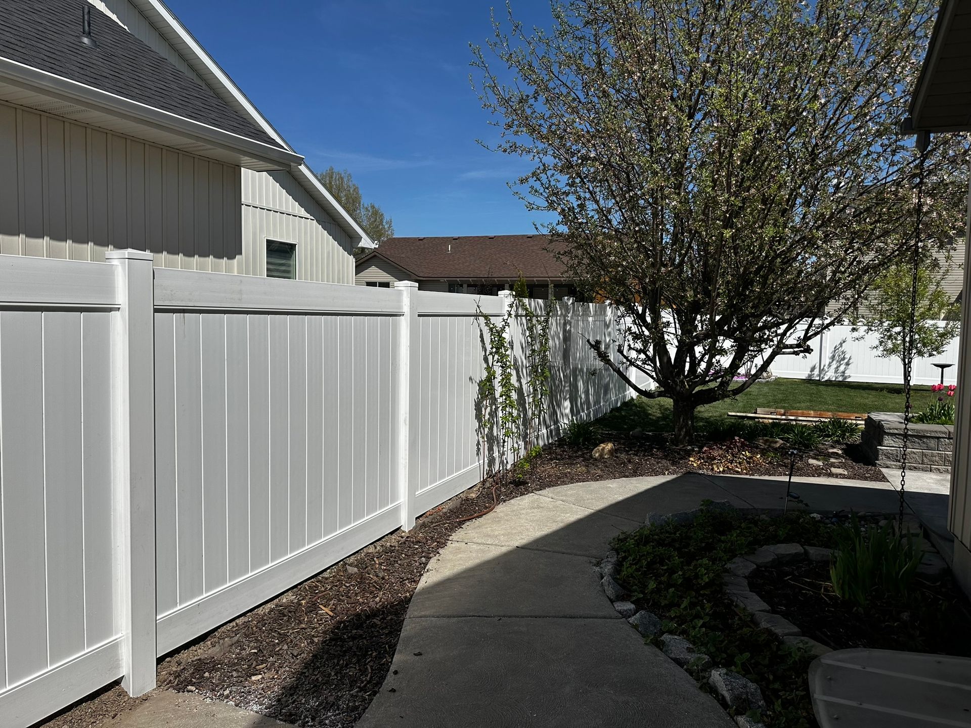 A white fence surrounds a sidewalk in front of a house.
