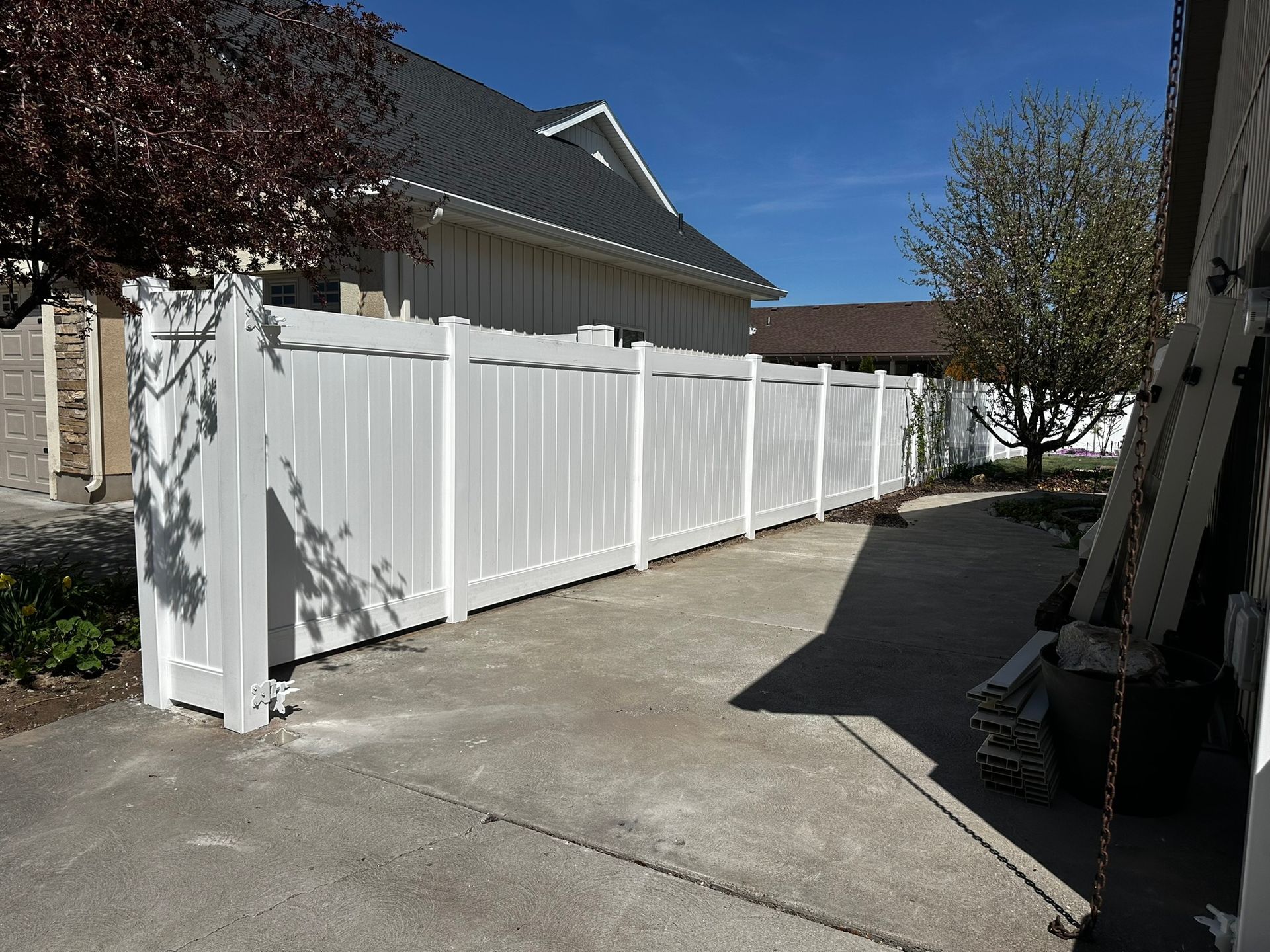 A white fence surrounds a driveway in front of a house.
