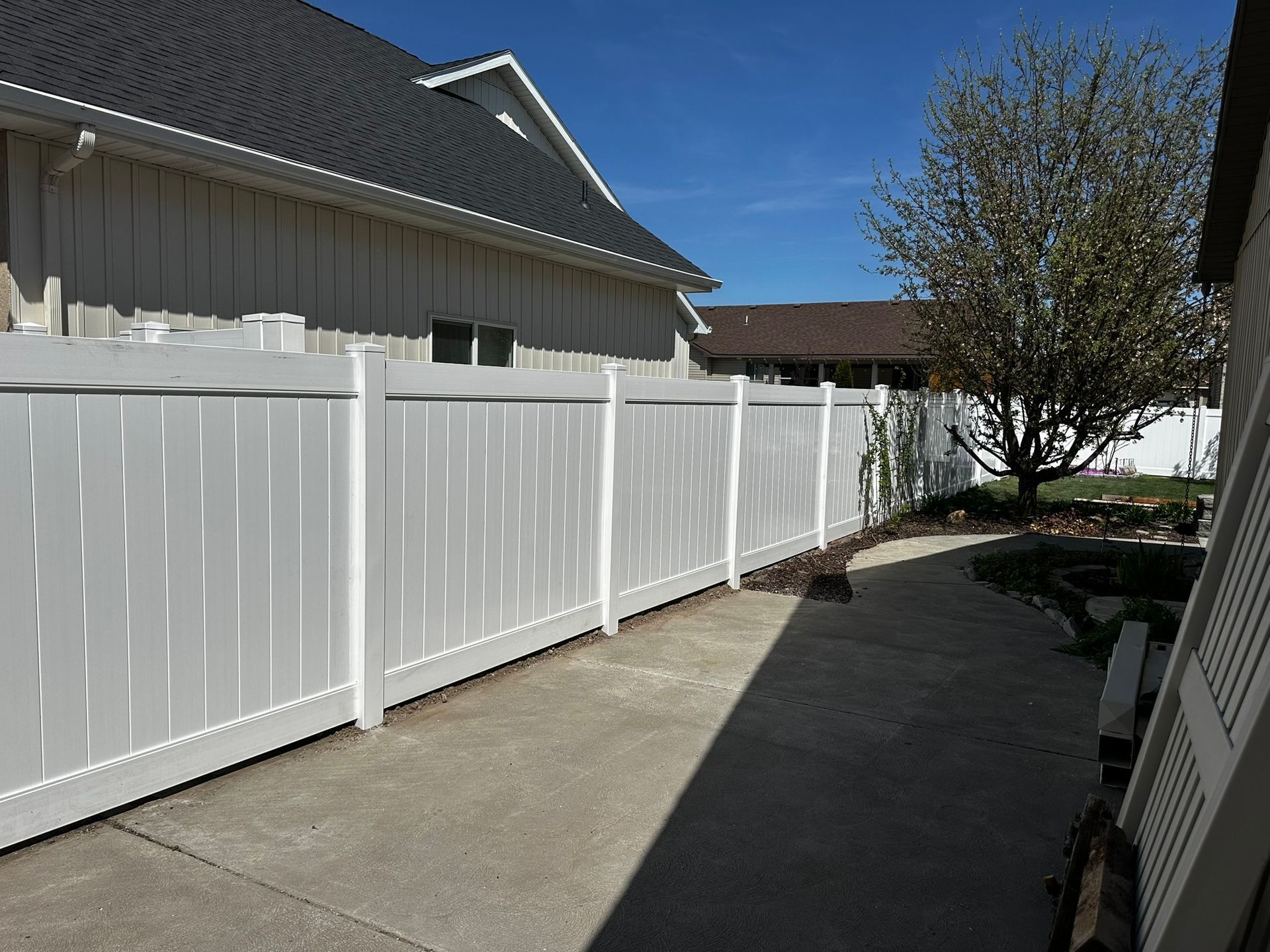 A white fence surrounds a patio in front of a house.