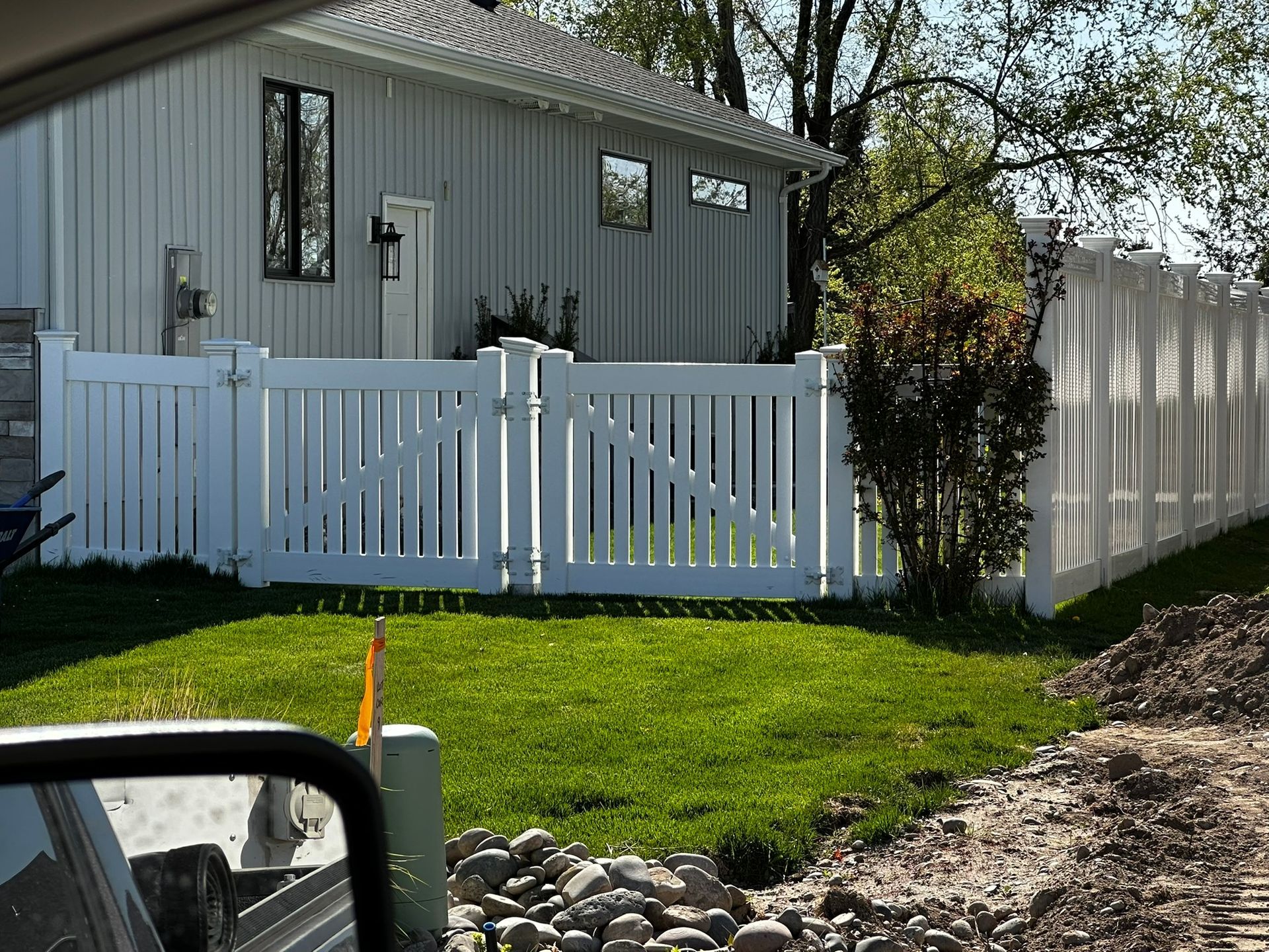 A white fence is in front of a white house.
