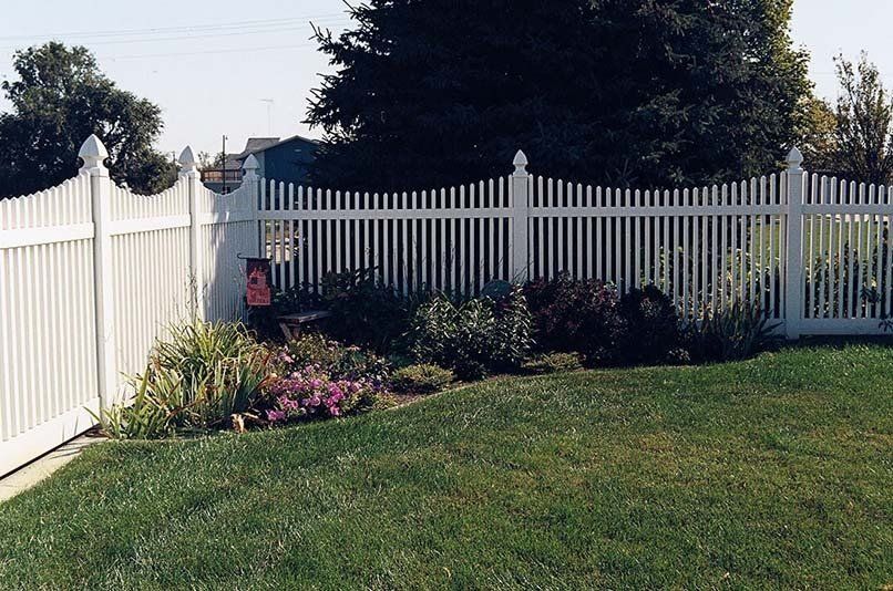 A white picket fence surrounds a lush green yard