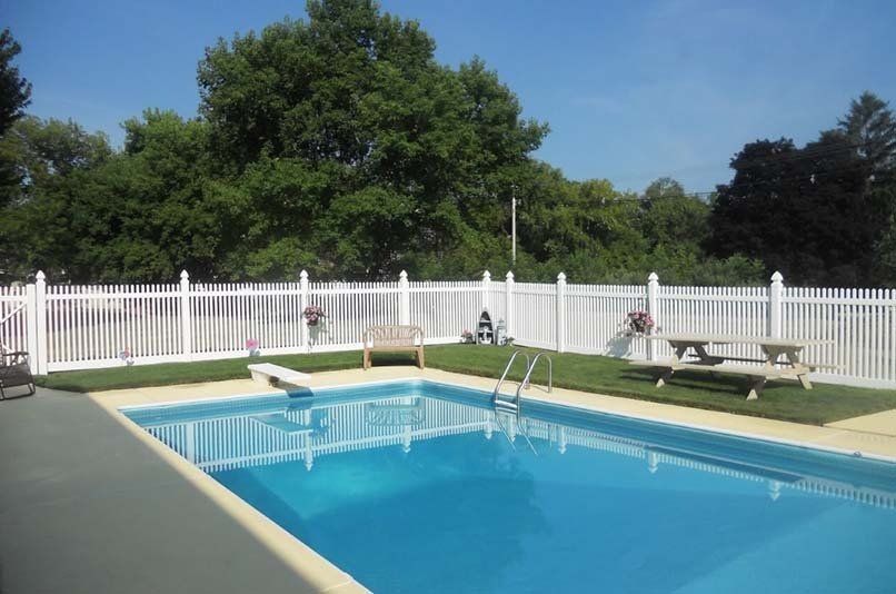 A large swimming pool with a white fence around it