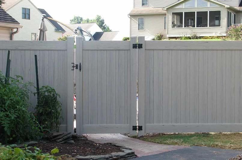 A white fence with a gate in front of a house