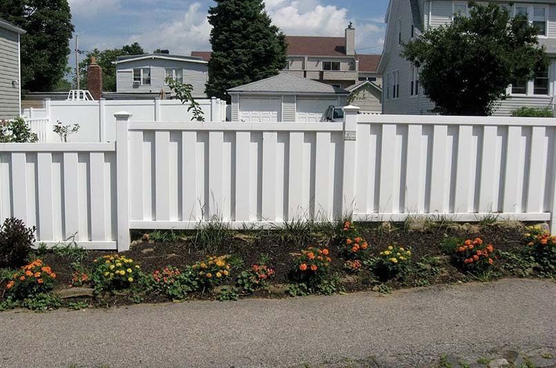A white fence with flowers in front of it
